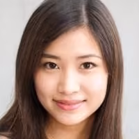 Young woman with long straight dark hair and a gentle smile, facing the camera against a neutral light background.